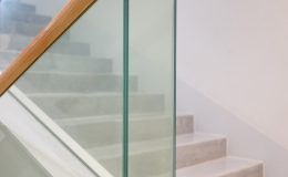 a stair case with glass railing and wooden handrail